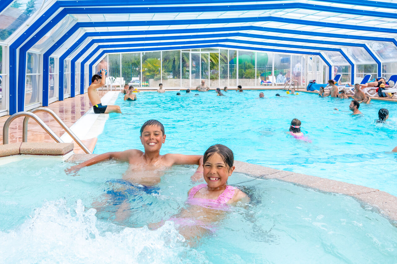 Indoor swimming pool with children and jacuzzi at VAGUES OCEANES Marina Landes campsite in Mimizan (40).
