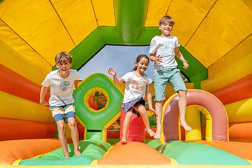 Children on colorful inflatable games at VAGUES OCEANES Marina Landes campsite.