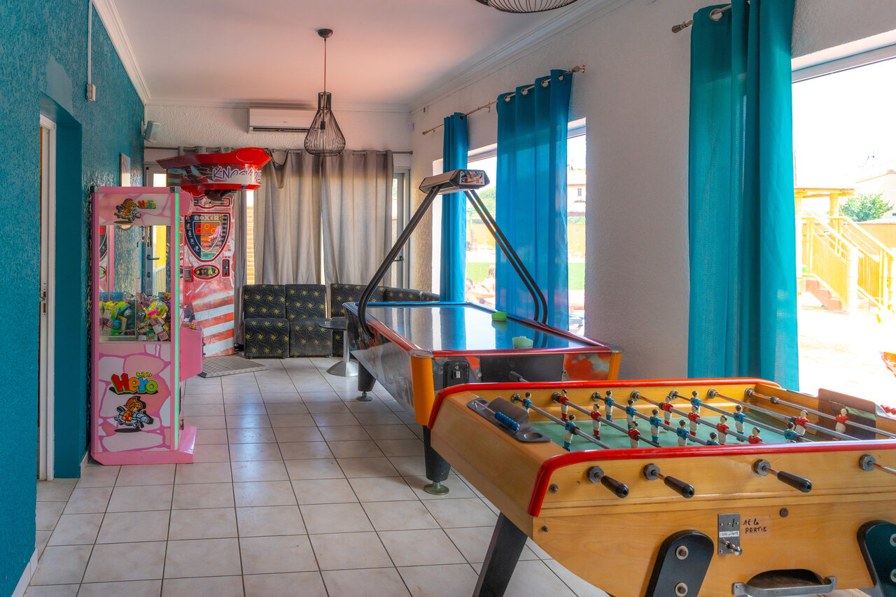 Game room with foosball, air hockey, and arcade machines at VAGUES OCEANES Marinette campsite in Ste Marie La Mer (66).