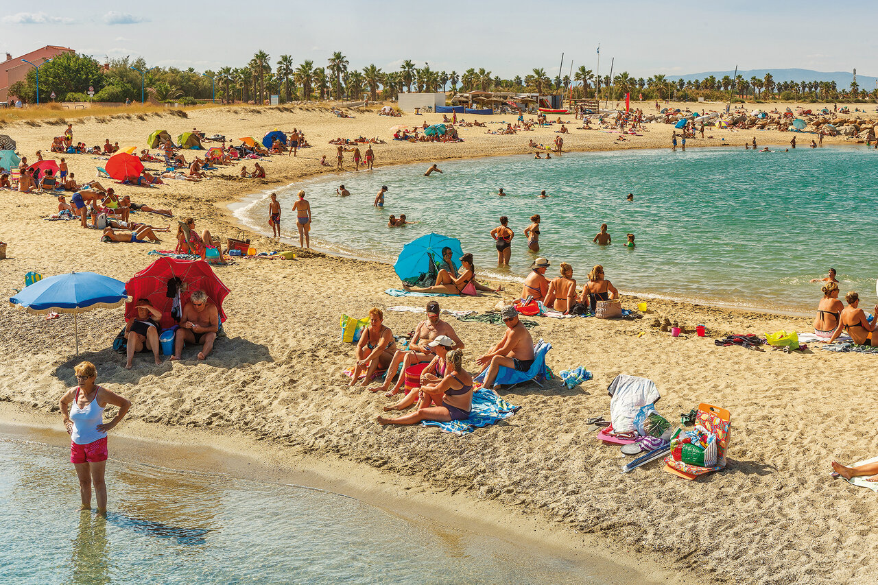 Lively sandy beach with swimmers and parasols at VAGUES OCEANES Marinette campsite (66).