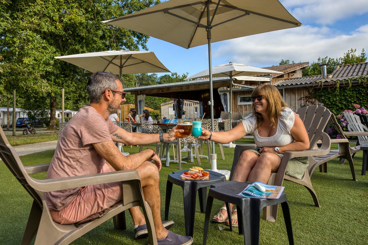 Couple toasting cocktails at the bar of CLICOCHIC M�doc Bleu campsite in Carcans (33).