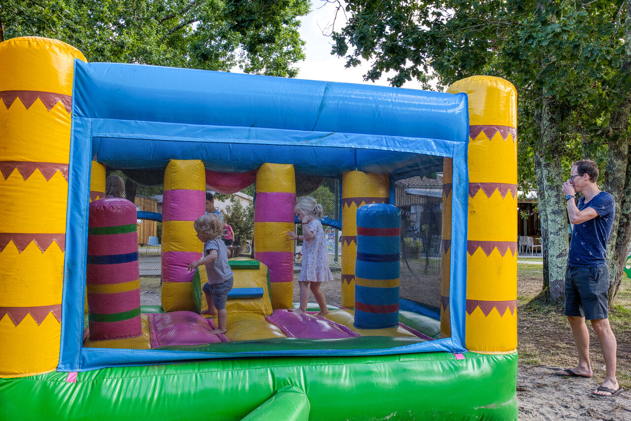Colorful inflatable bouncy castle with kids at CLICOCHIC M�doc Bleu campsite in Carcans (33).