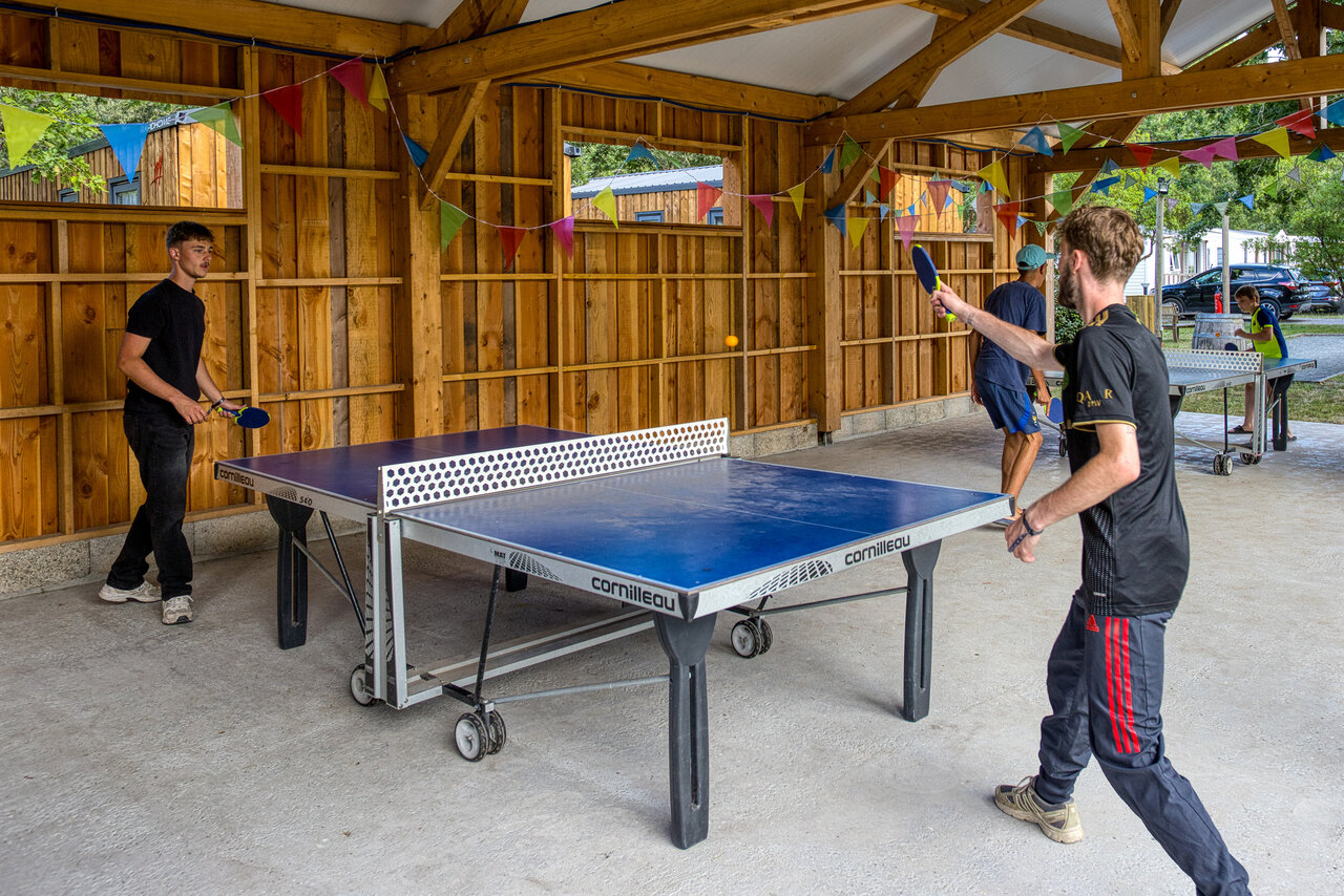 Table tennis players under decorated shelter at CLICOCHIC M�doc Bleu campsite in Carcans (33).