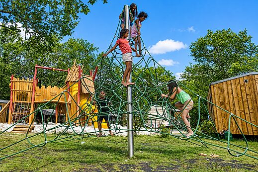 Children playing on rope climbing structure at CLICOCHIC Médoc Bleu campsite.