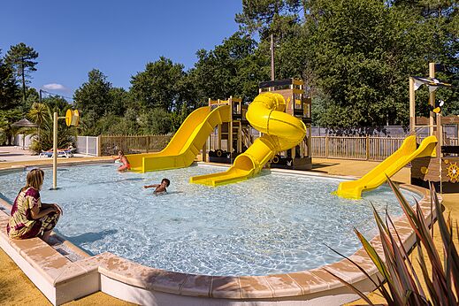 Swimming pool with yellow water slides at CLICOCHIC Médoc Bleu campsite in Carcans (33).