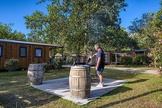 Man grilling in front of Mobile homes at CLICOCHIC Médoc Bleu Carcans (33).