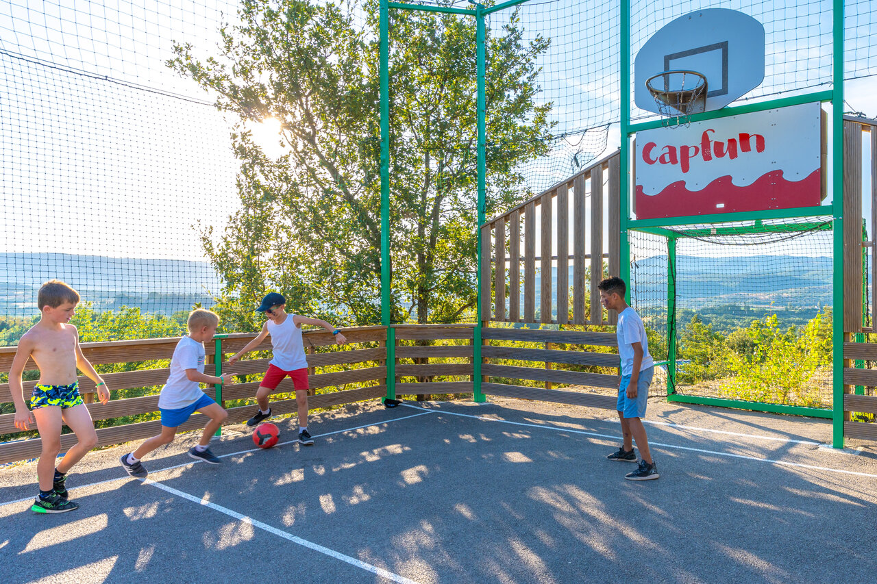 Children playing football on multi-sport court CAPFUN Merle Roux, Baix (07).
