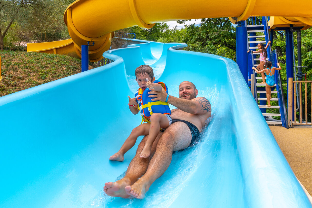 Father and child on giant water slide at CAPFUN Merle Roux campsite in Baix (07).