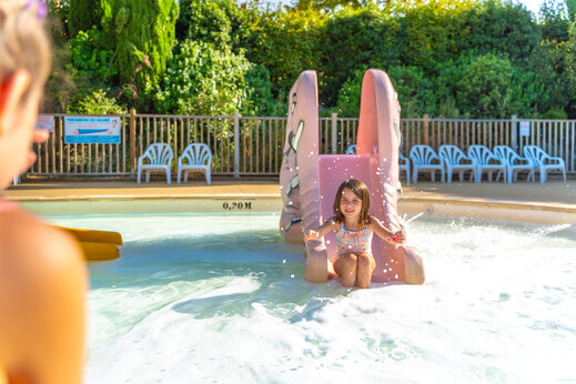 Little girl on water slide in shallow pool at CAPFUN Merle Roux campsite in Baix (07).