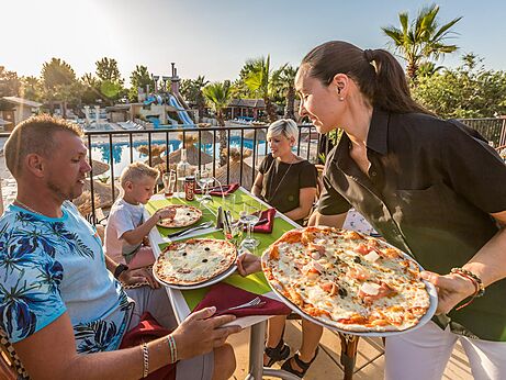 Family eating pizzas at restaurant, pool view, camping CAPFUN Mer et Soleil in Cap d'Agde (34).