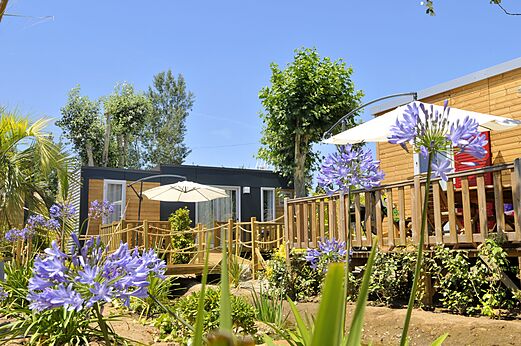 Modern mobile homes with wooden deck and parasols at CAPFUN Mer et Soleil campsite in Cap d'Agde (34).