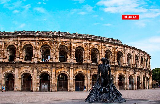 Roman amphitheater of Nîmes and bullfighter statue, a place to visit in Occitania.