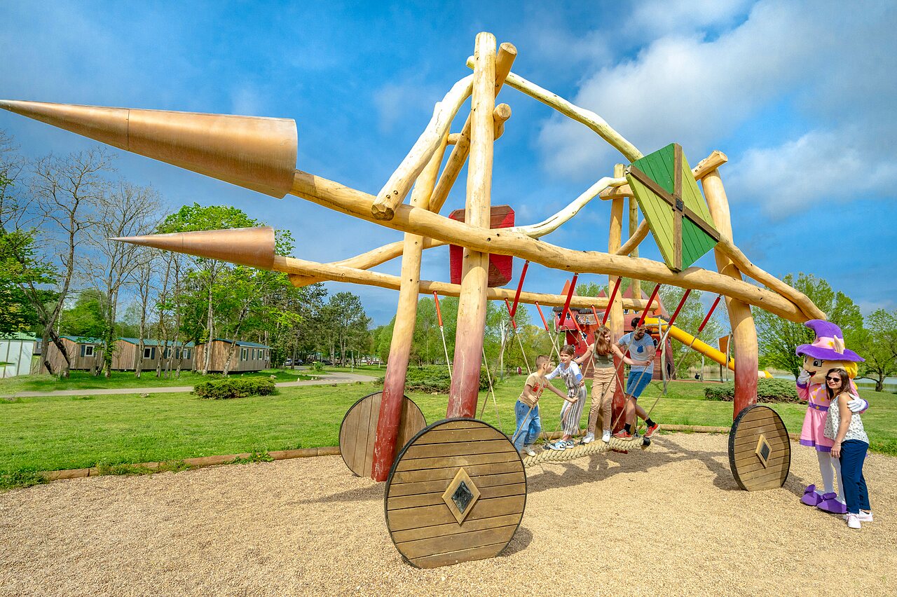 Large wooden play structure with children and mascot at CAPFUN Mirabelle campsite in VOLSTROFF (57).