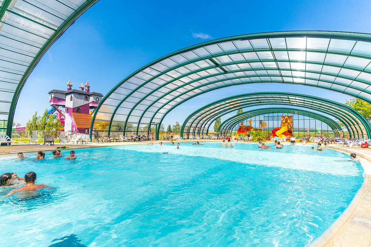 Covered swimming pool with slides and water games at CAPFUN Mirabelle campsite in VOLSTROFF (57).