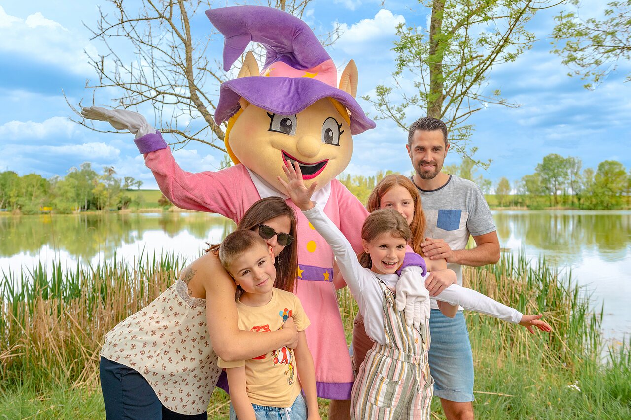 Mascot and smiling family by the lake at CAPFUN Mirabelle campsite in VOLSTROFF (57).