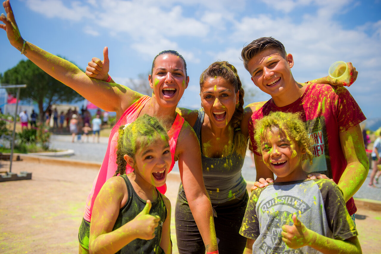 Smiling family covered in color powder during animation at camping CAPFUN Mirmanda.