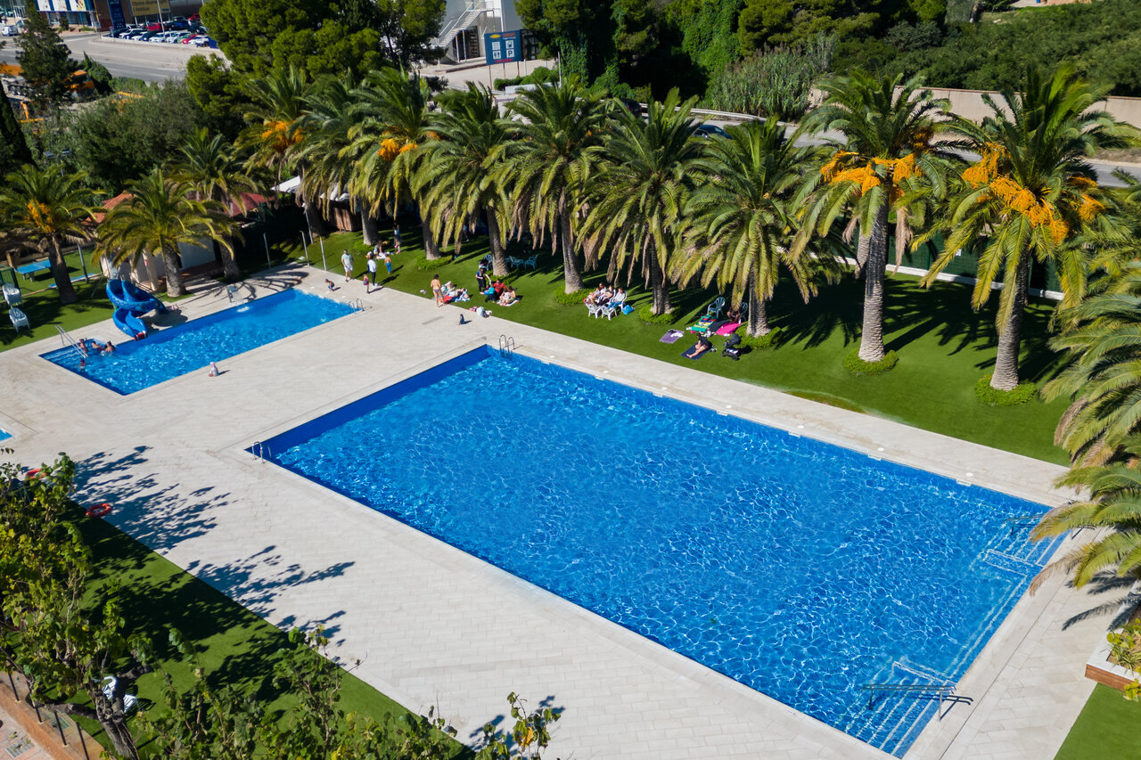 Outdoor pools with slide and palm trees at CAPFUN Mirmanda campsite in Cambrils (43).