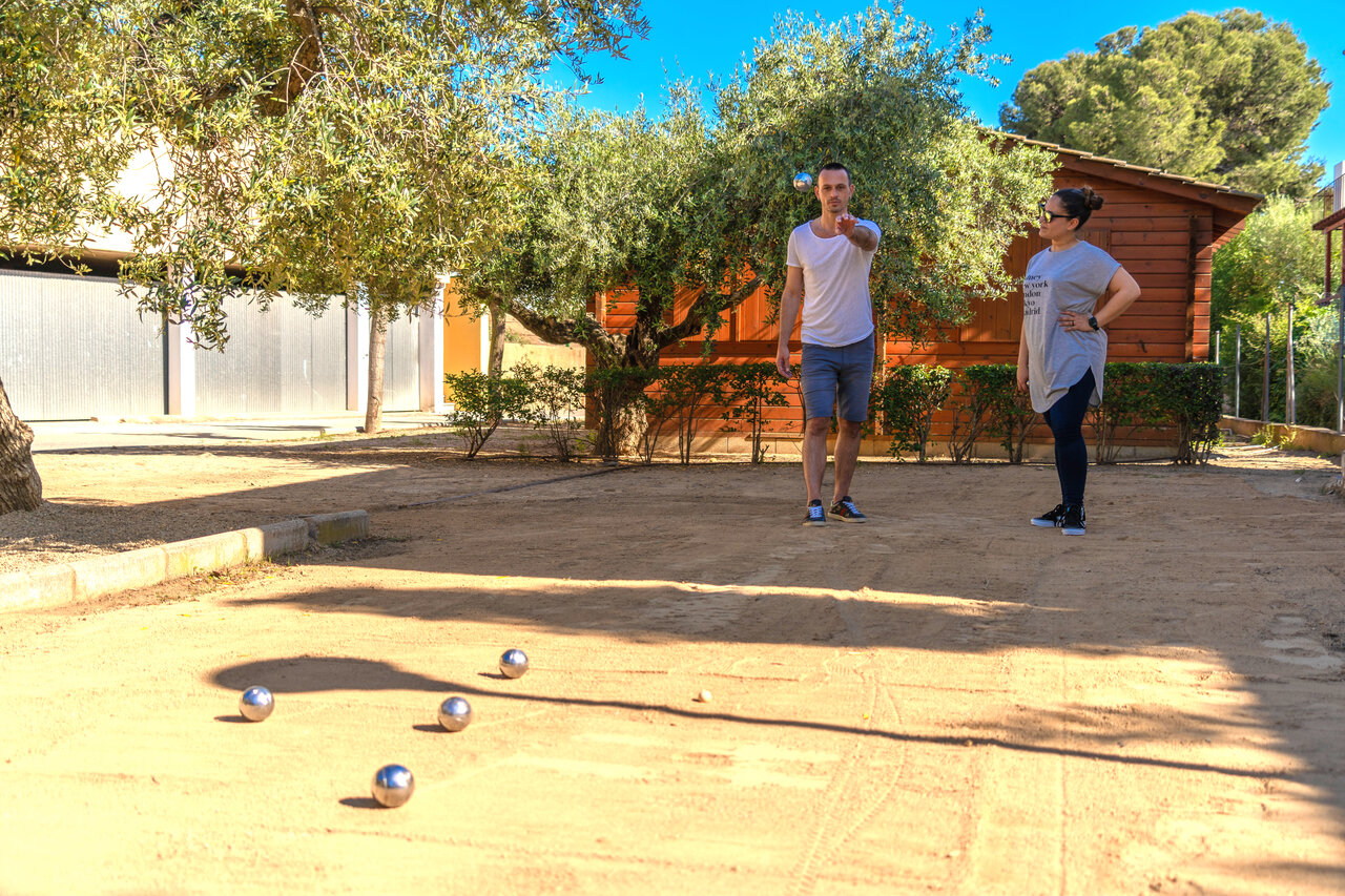 Shaded petanque court with players at CAPFUN Mirmanda campsite, Cambrils - Vinyols i els Arcs.