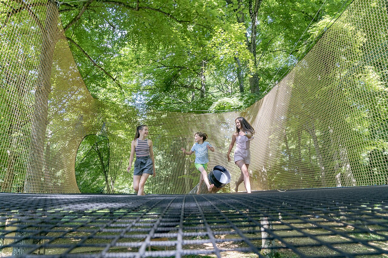 Kids play on suspended nets among trees at CAPFUN Montsabert campsite.