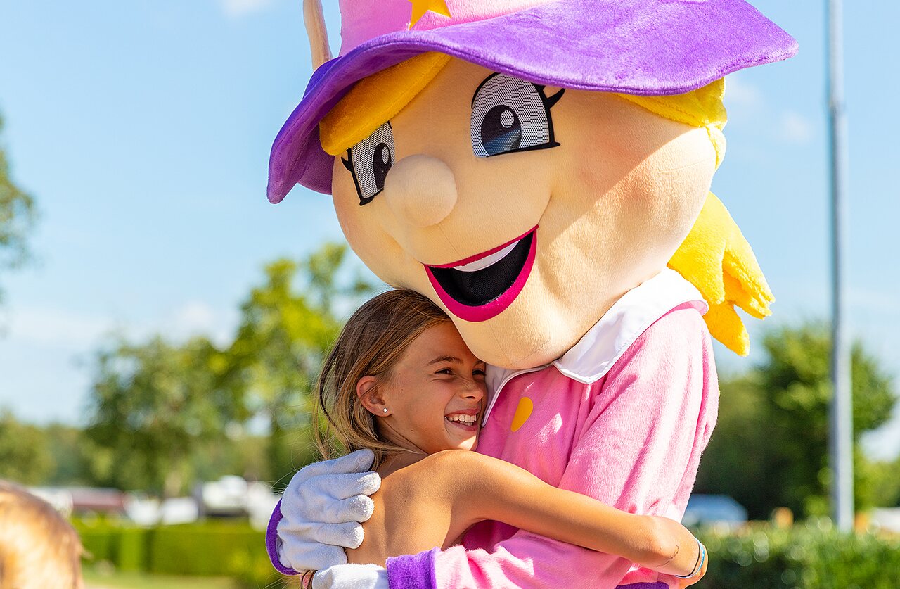 Smiling child hugging the camping mascot at CAPFUN Montsabert campsite in COUTURES (49).