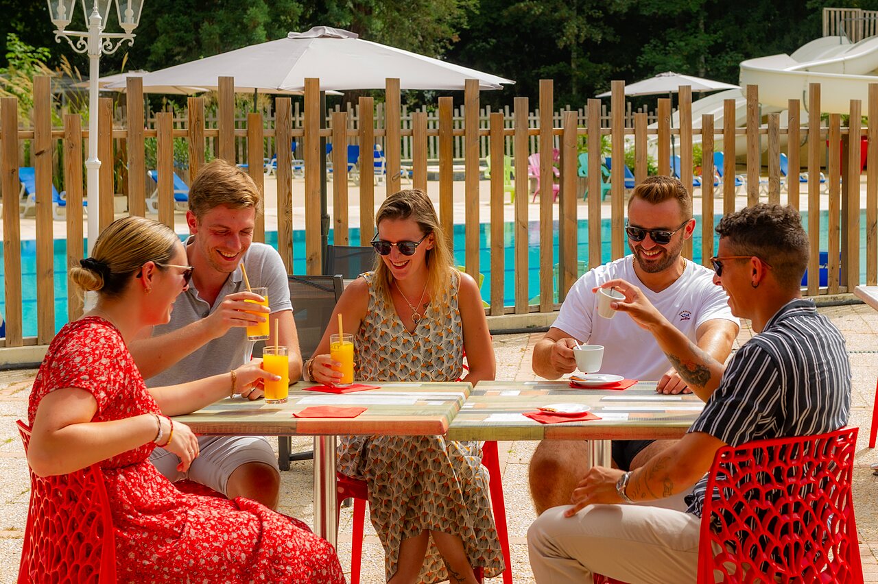 Friends drinking at the bar, pool in background, camping CAPFUN Montsabert in COUTURES (49).