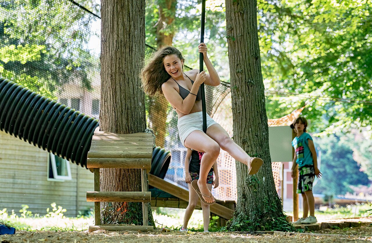 Smiling girl on rope swing, adventure course, CAPFUN Montsabert campsite in COUTURES (49).