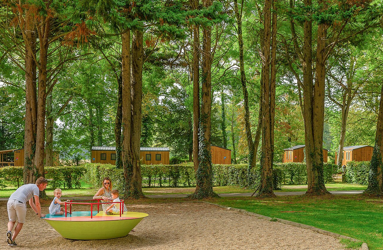 Family on colorful merry-go-round, Mobile homes at CAPFUN Montsabert campsite in COUTURES (49).