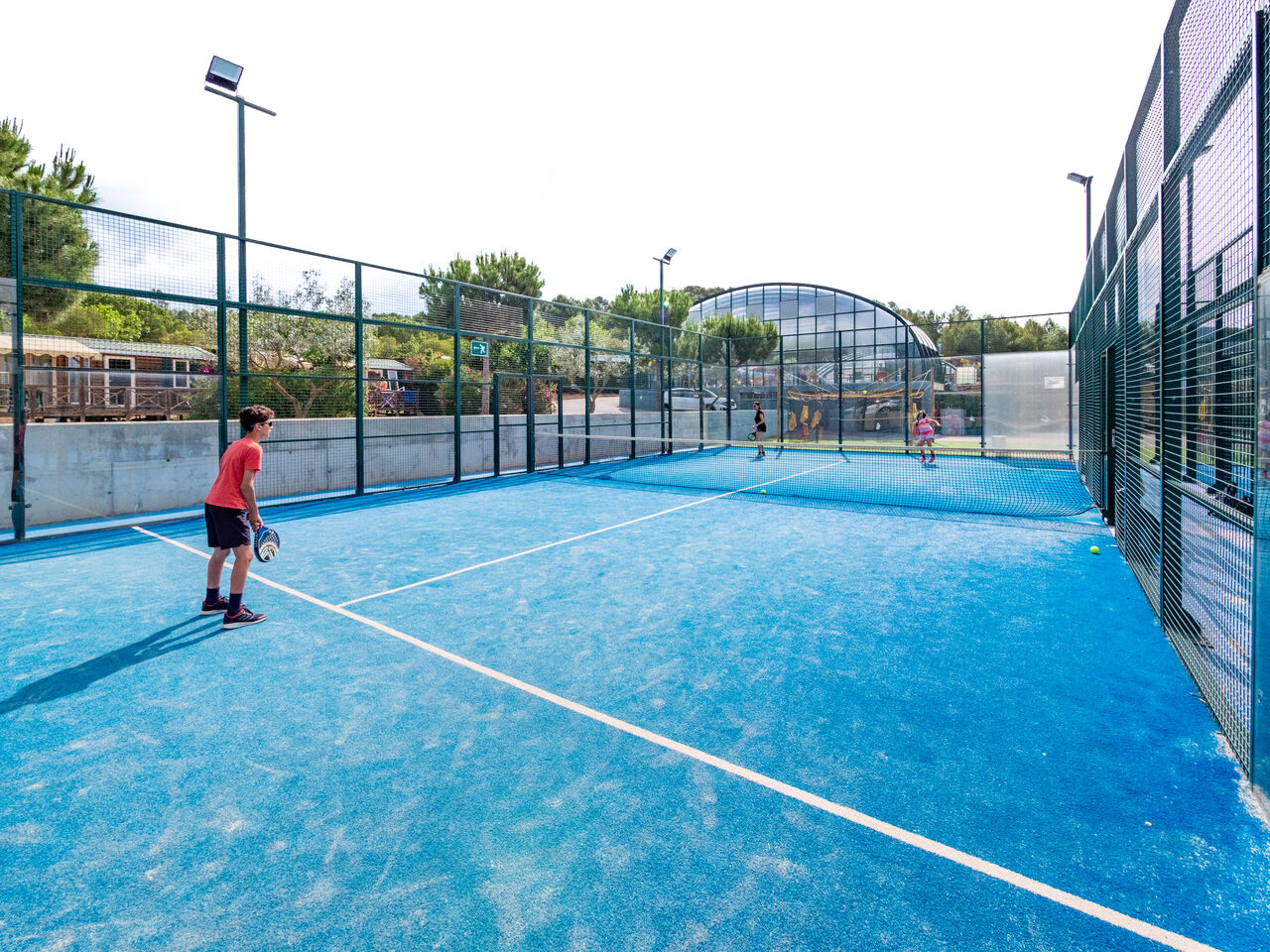 Blue padel court with players, sporting activity at CAPFUN Montblanc Park campsite.
