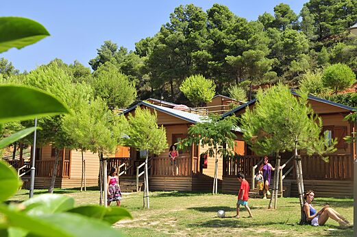 Wooden Mobile Homes with terraces and families at CAPFUN Montblanc Park campsite in Montblanc (43).