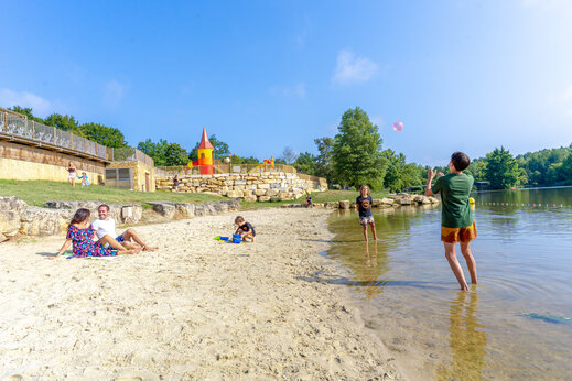 Sandy beach by the lake with playground at CAPFUN Moulinal campsite in BIRON (24)