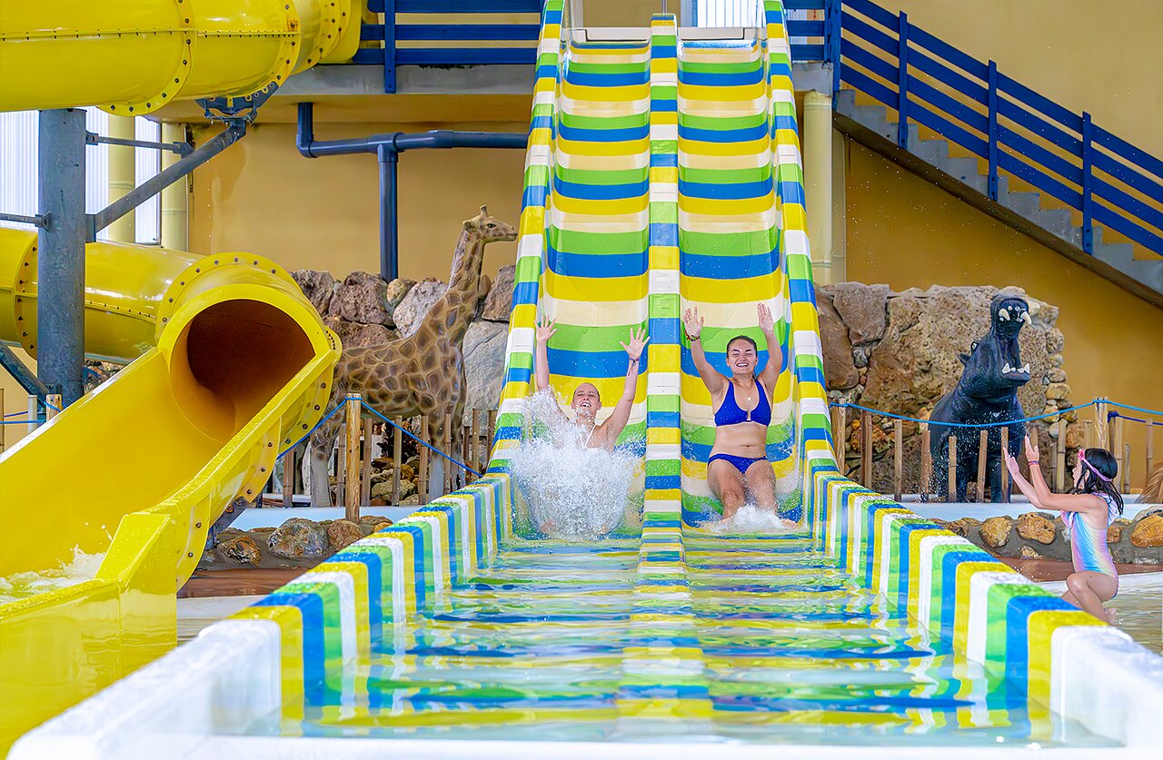Guests enjoying colorful water slides in indoor pool, VAGUES OCEANES Moulin de Cadillac campsite (56).