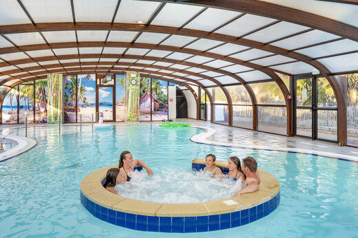 Indoor swimming pool with jacuzzi and family enjoying at VAGUES OCEANES Moustoir campsite in Carnac (56).