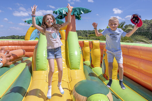 Children jumping on a giant inflatable play structure at VAGUES OCEANES Moustoir campsite in Carnac (56).