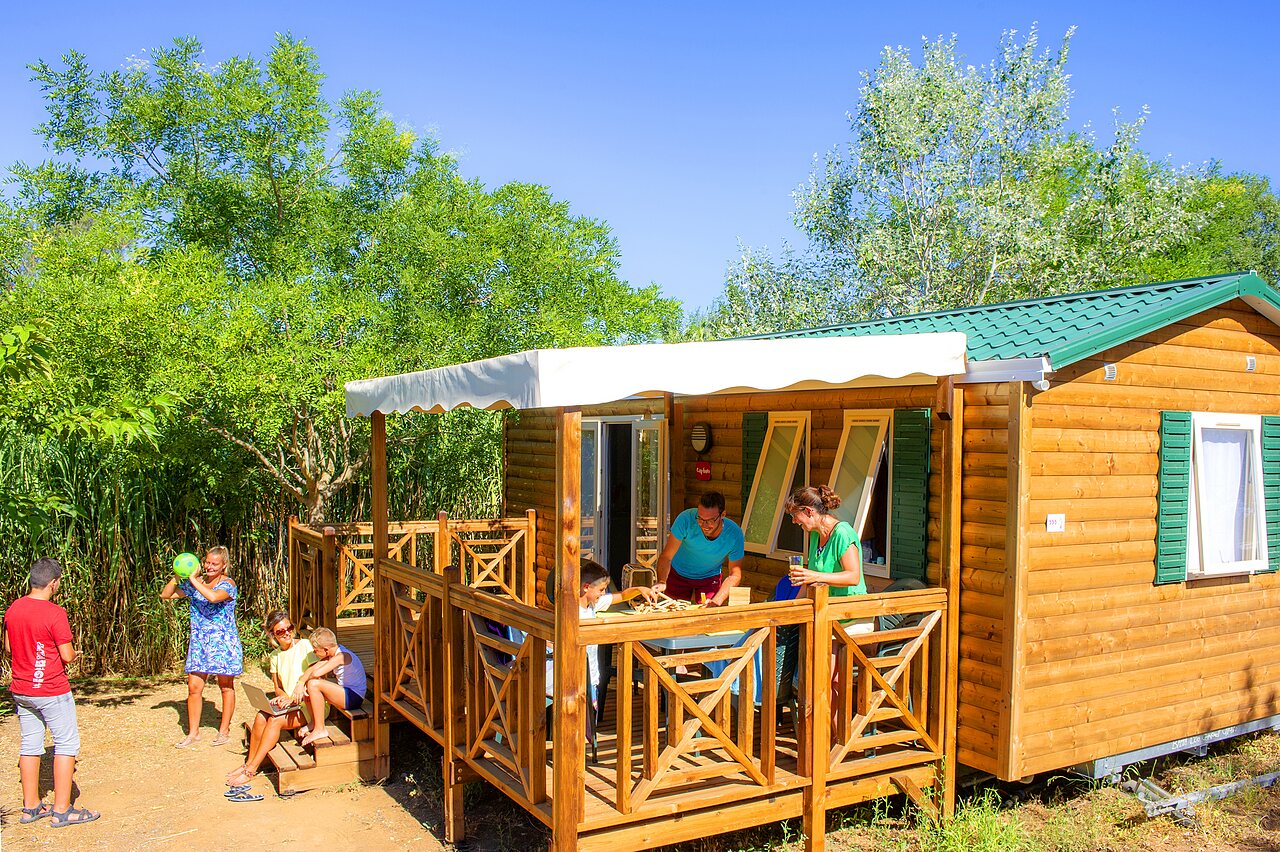 Family enjoying wooden Mobil-home terrace at CAPFUN La Nina campsite in Agde (34).