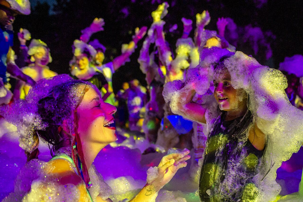 Lively foam party with smiling children and adults at CAPFUN La Nina campsite in Agde (34).