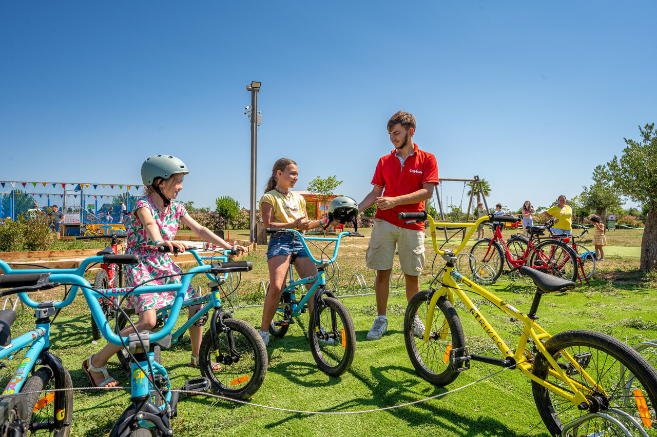 Children and animator with bikes and helmets for activity at CAPFUN Ondines campsite in Vias Plage.