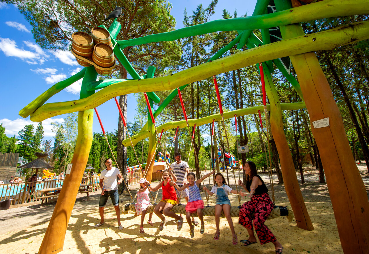 Family on giant swing, playground, swimming pool, CAPFUN Or campsite, La Grande Motte.