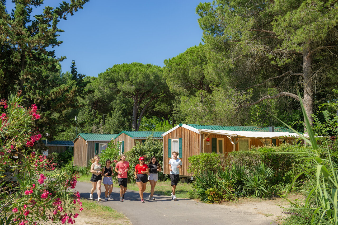 Young joggers and wooden mobile homes at CAPFUN Or, La Grande Motte (34).