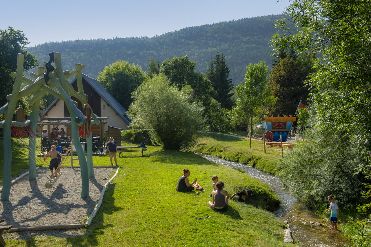 Children's playground, stream and greenery at CAPFUN Oursi�re campsite in Villard de Lans (38).
