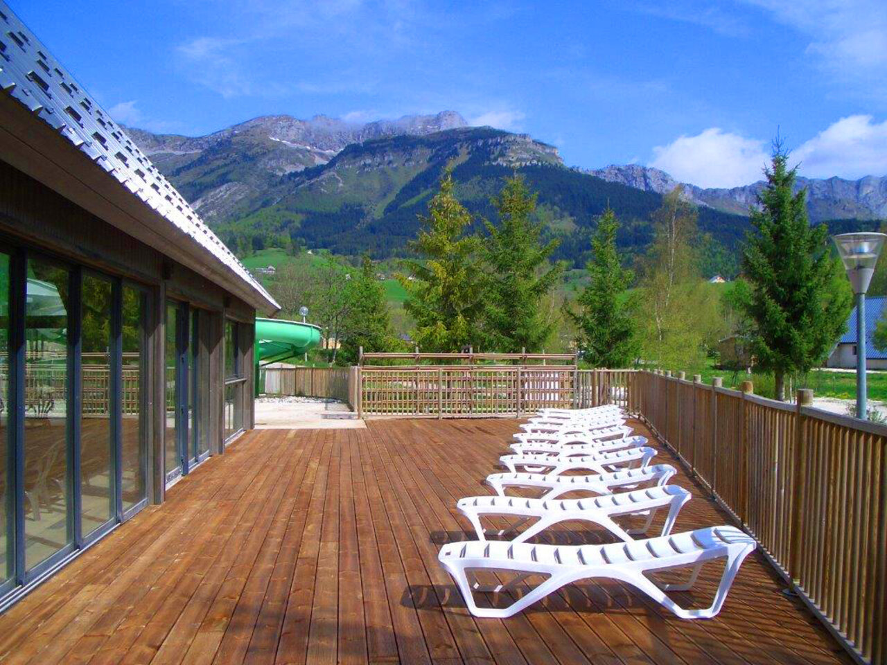 Wooden deck, sun loungers, waterslide, mountains at CAPFUN Oursi�re campsite in Villard de Lans (38).