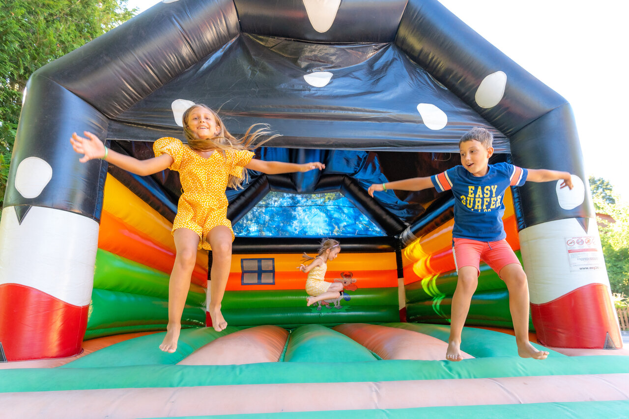 Children jumping on colorful bouncy castle at CAPFUN Oursi�re campsite in Villard de Lans (38).