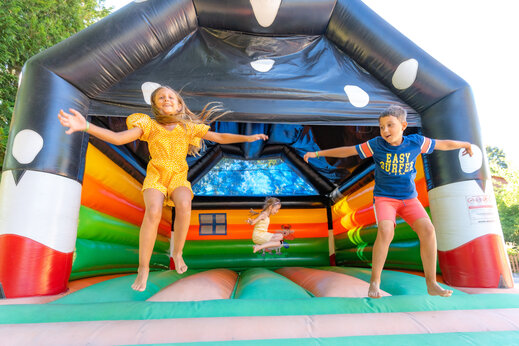 Children happily jumping on a colorful bouncy castle at CAPFUN Oursi�re campsite in Villard de Lans (38).