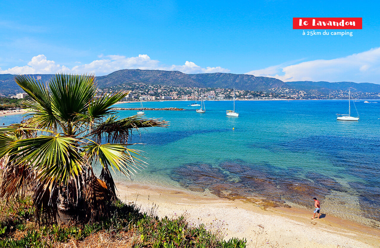 Sandy beach, turquoise sea and boats in Le Lavandou, nearby tourist destination.