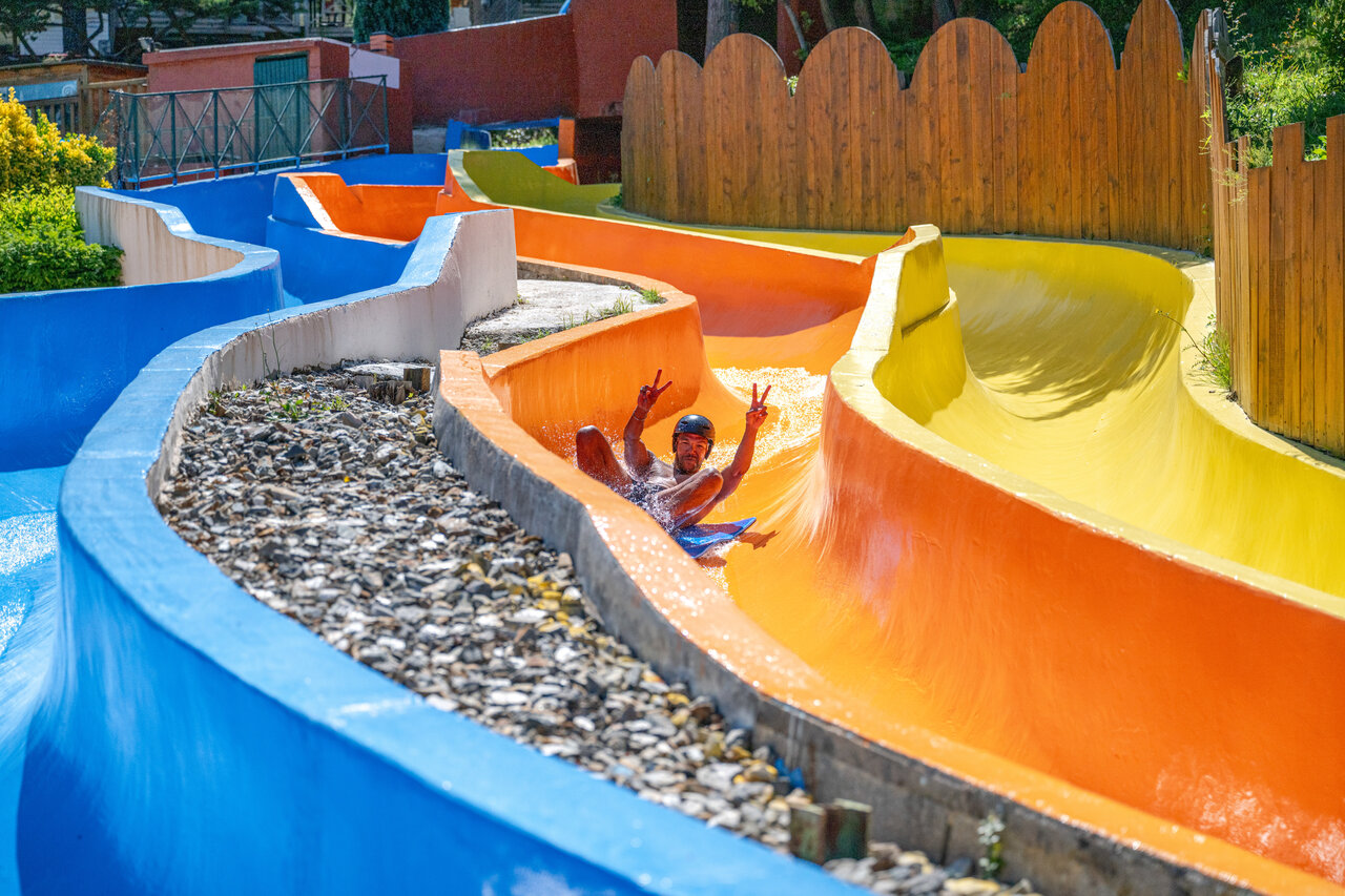 Man on colorful water slide at CAPFUN Pachacaid campsite, La Mole.