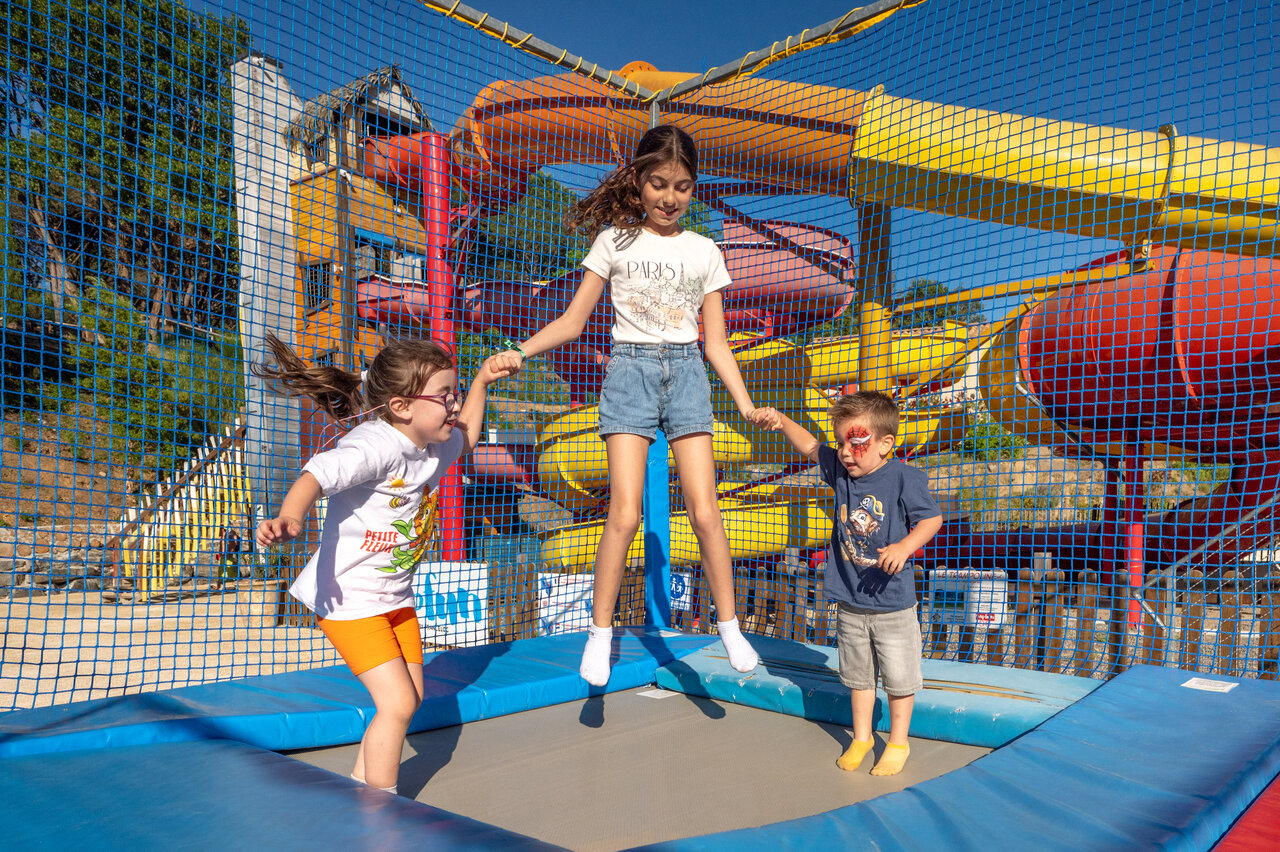 Children jumping on trampoline, colorful water slides at CAPFUN Pachacaid campsite in La Mole (83).