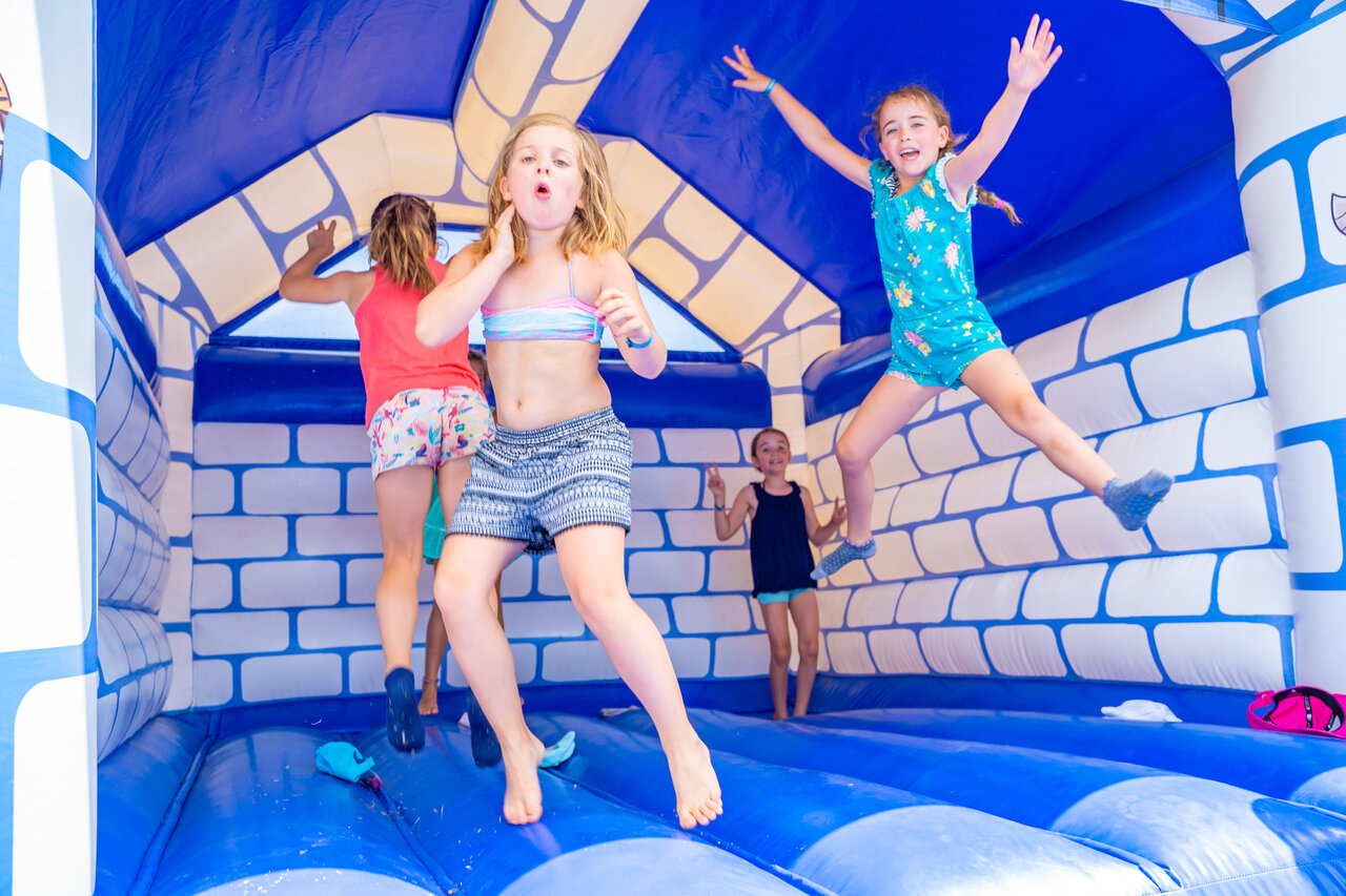 Children jumping in a blue and white bouncy castle at CAPFUN Pachacaid campsite in La Mole (83).