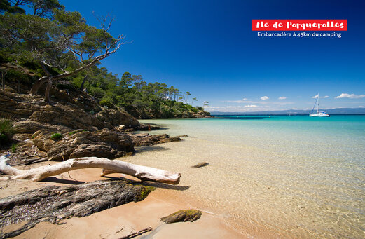 Paradise beach of Porquerolles Island, turquoise waters, rocky coast and sailboat.