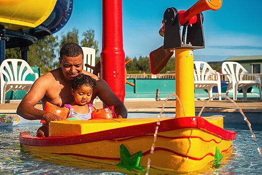 Child and father playing in the water play area at CAPFUN Pachy campsite in FOSSES LA VILLE.