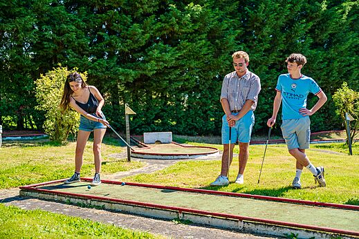 Young people playing mini-golf on a green course at CAPFUN Pachy campsite in FOSSES LA VILLE.