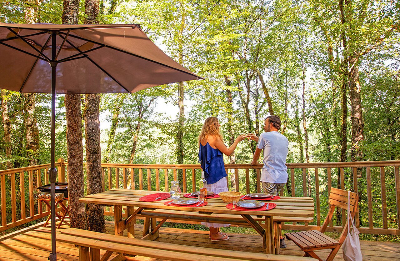 Couple on wooden terrace, at VAGUES OCEANES Paille Basse campsite in Souillac (46).